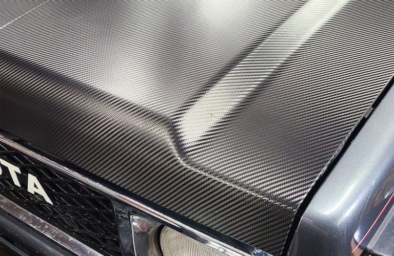 A Close Up of a Carbon-Fiber Wrap Material on the Hood of a Toyota